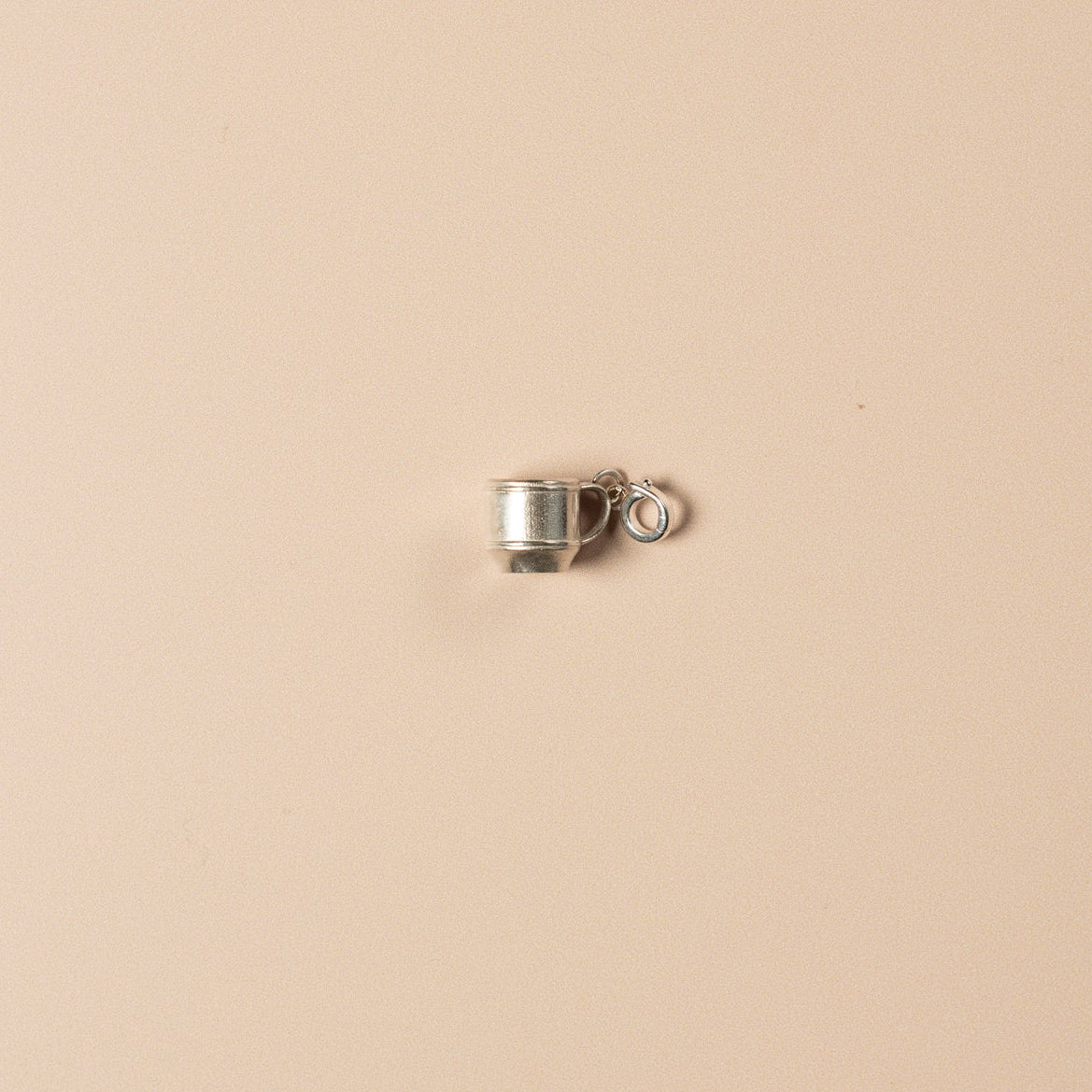 Small silver cup charm on a beige background