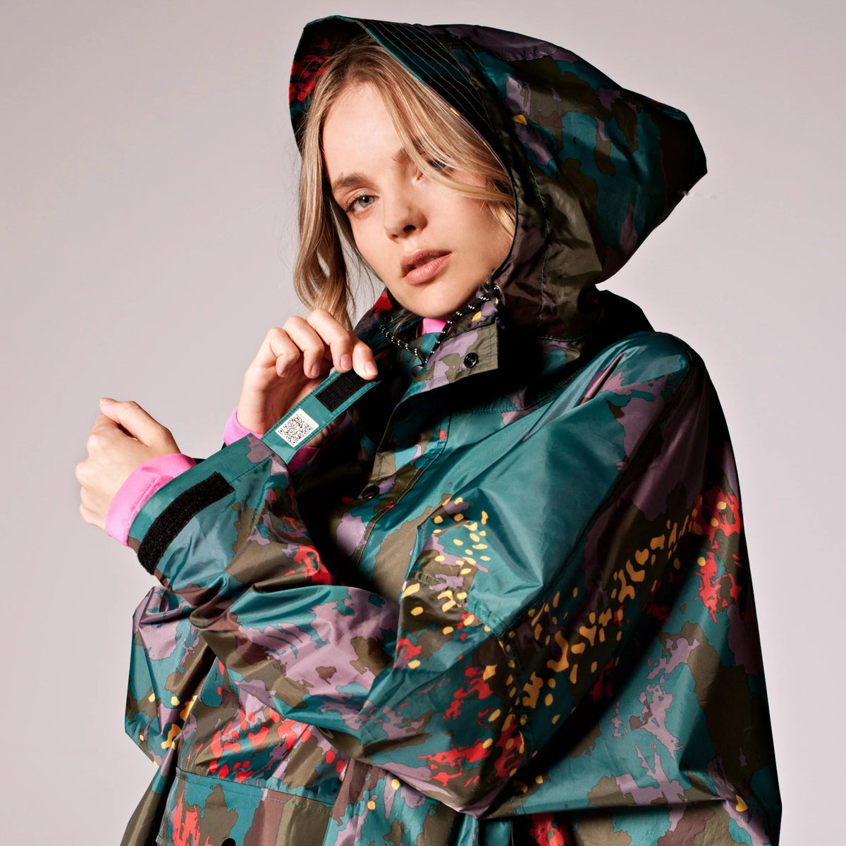 Person wearing a colorful raincoat with a patterned design on a plain background
