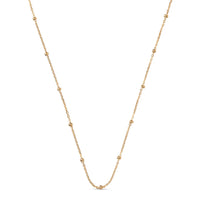 A delicate gold chain necklace featuring evenly spaced, small polished bead accents, displayed against a solid white background.