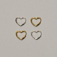 Four small open heart-shaped metal findings arranged in a 2x2 grid on a light gray background. Two are silver-toned and two are gold-toned.