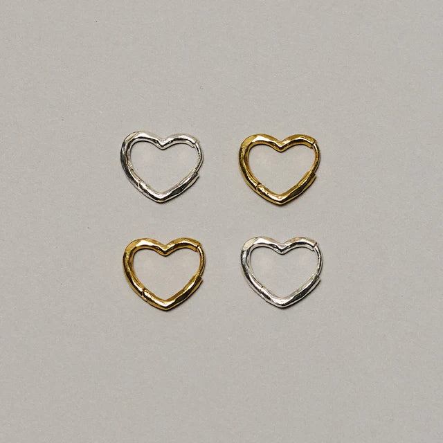 Four small open heart-shaped metal findings arranged in a 2x2 grid on a light gray background. Two are silver-toned and two are gold-toned.