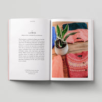 Open page of Eco London book featuring a photograph of colouful folded sweaters on a table with a potted plant.