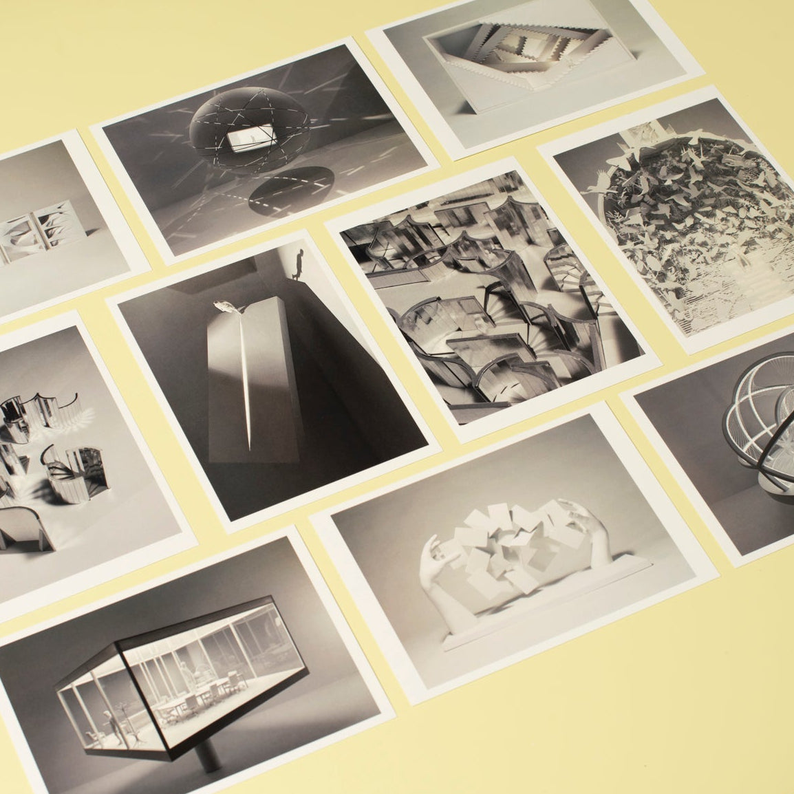 A collection of nine black and white architectural photography prints arranged in a 3x3 grid on a pale yellow background board.