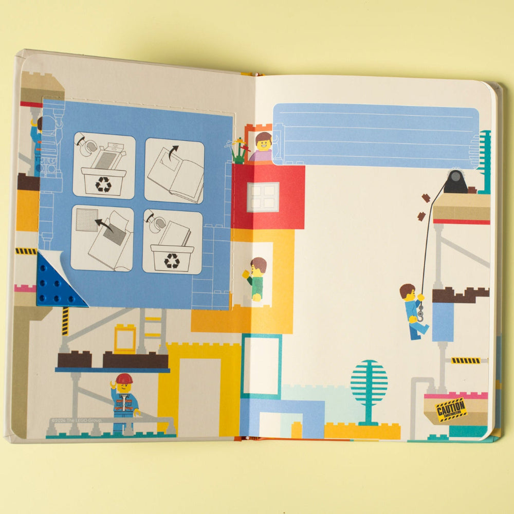 An open illustrated notebook or book spread on a pale yellow background, featuring a colorful architectural scene with small worker figures, blue panels, and construction-like details.