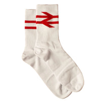 A pair of white crew socks with a red geometric arrow-like logo on the cuff, displayed on a solid dark red background.