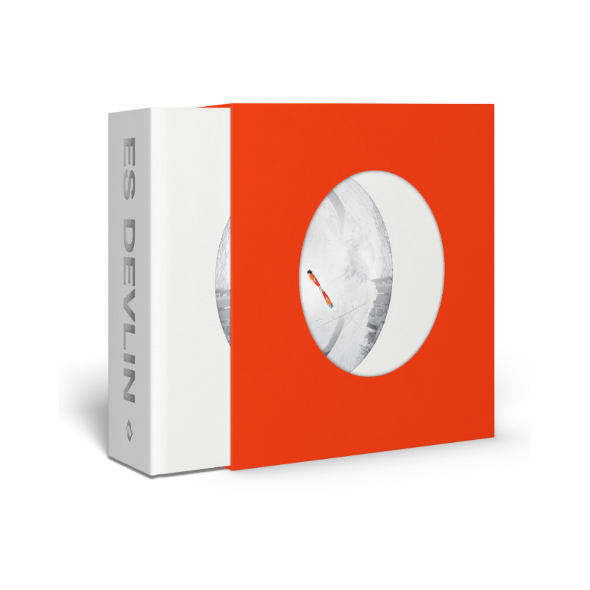 Red and white packaging box with a circular cutout displaying a white Es Devlin book
