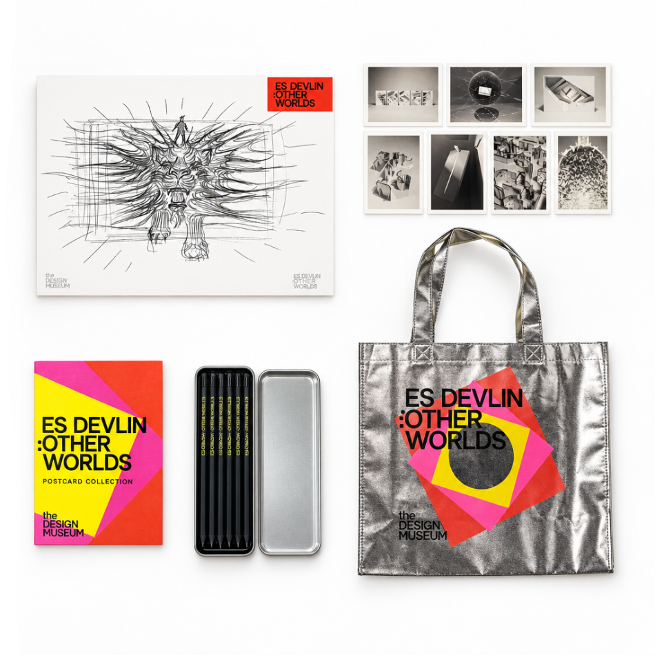 A curated flat lay of the 'Es Devlín: Other Worlds' forecastcard collection by The Design Museum, featuring a large sketch print, a metallic tote bag, a colorful booklet, a silver tin, and a row of small black-and-white photo prints on a white background.