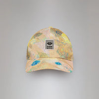 A baseball cap with a pastel multicolor paint-splatter pattern in yellow, pink, and blue, featuring a black 'RAIN KISS' logo patch on the front, set against a neutral gray background.