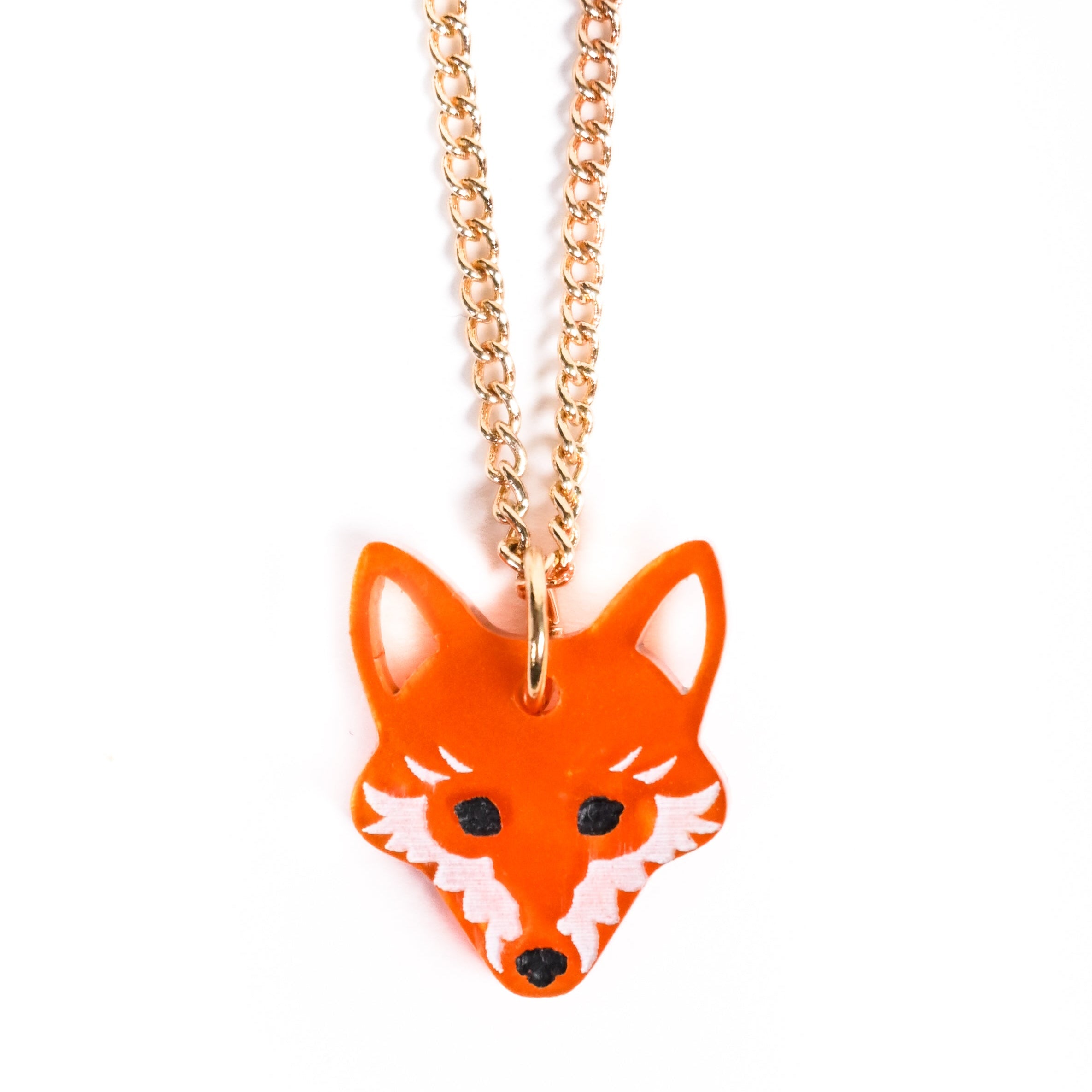 Orange fox-shaped pendant on a gold chain against a white background