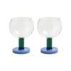 Two glass candle holders with green stems and blue bases on a white background