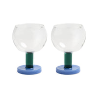 Two glass candle holders with green stems and blue bases on a white background