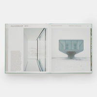 Open page of Glass Houses book featuring a photograph of a floating glass structured house in a snowy landscape.