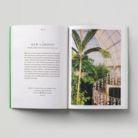 Open page of London Green Spaces book featuring a photograph of the inside of Kew Gardens with a palm tree and a staircase.