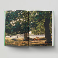 Open page of London Green Spaces book featuring a photograph of a deer in Richmond Park amongst some trees.