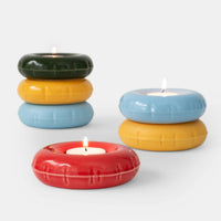 Colourful inflatable ceramic candle holders with lit candles on a white background