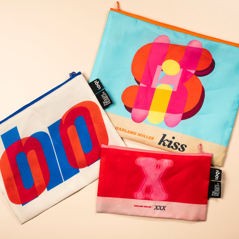 Three colorful Harland Miller pouches with abstract designs and text on a beige background