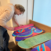 Person arranging colorful skateboard decks on a wooden surface.