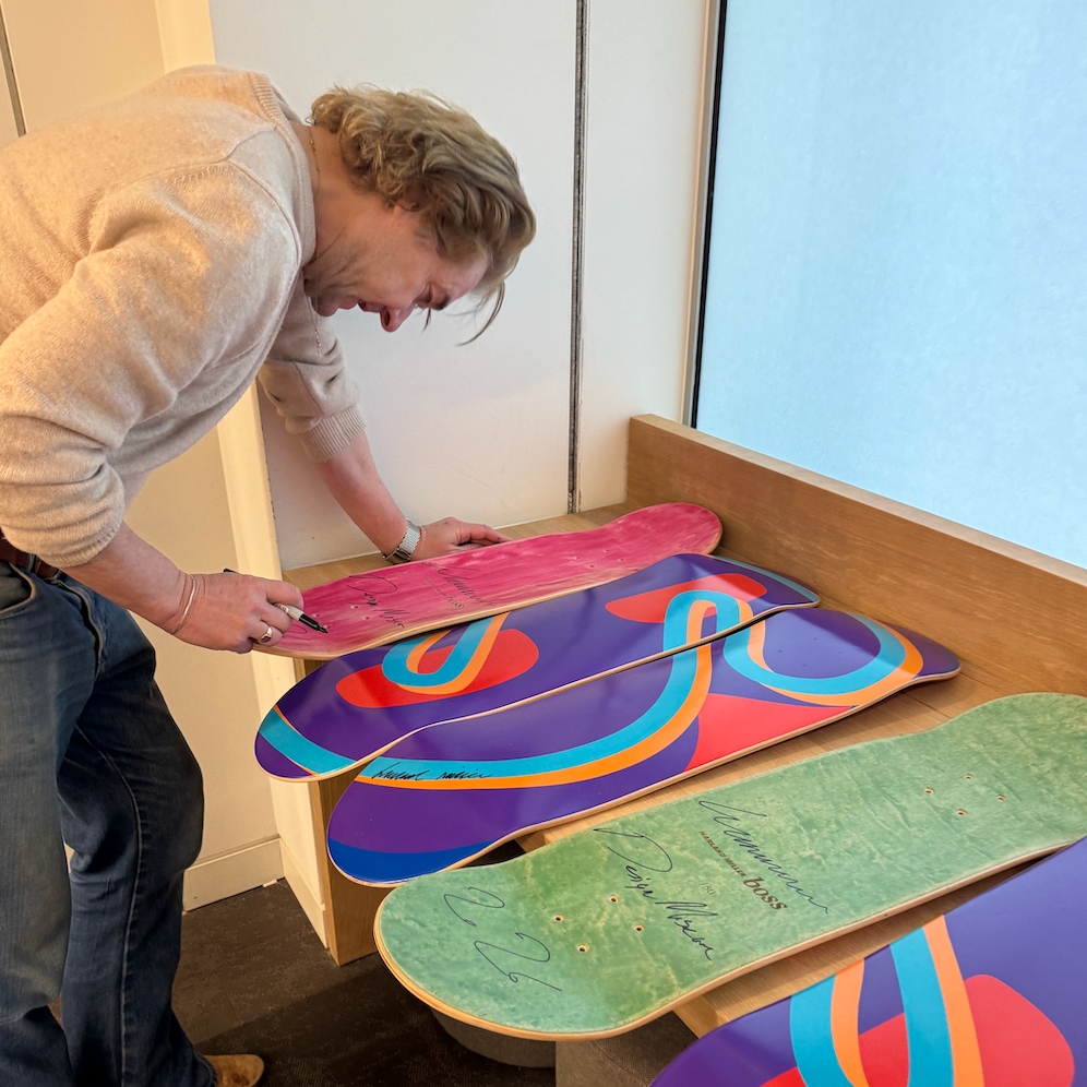 Person arranging colorful skateboard decks on a wooden surface.