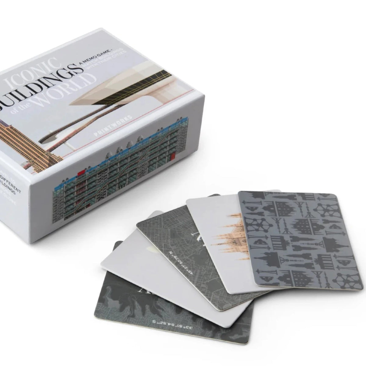 Spread out buildings game cards with grey designs next to a matching box on a white surface.