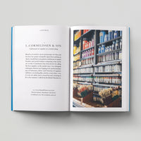 Open page of Independent London book featuring a photograph of an art shop with paints of various colours and paintbrushes.