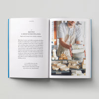 Open page of Independent London book featuring a photograph of a person holding cheese in a cheesmongers shop.