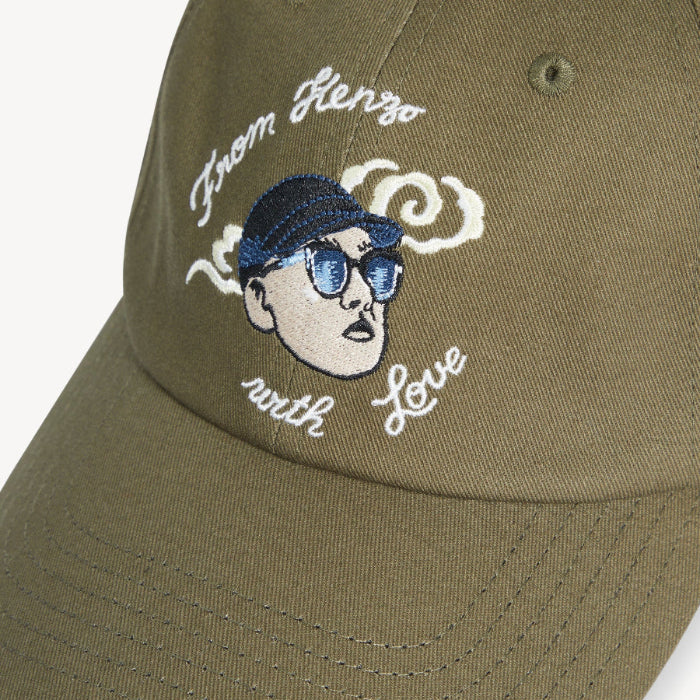 Green cap with embroidered design and text on a white background