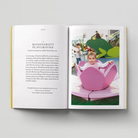 Open page of Kids London book featuring a photograph of a child in a pink wooden flower.