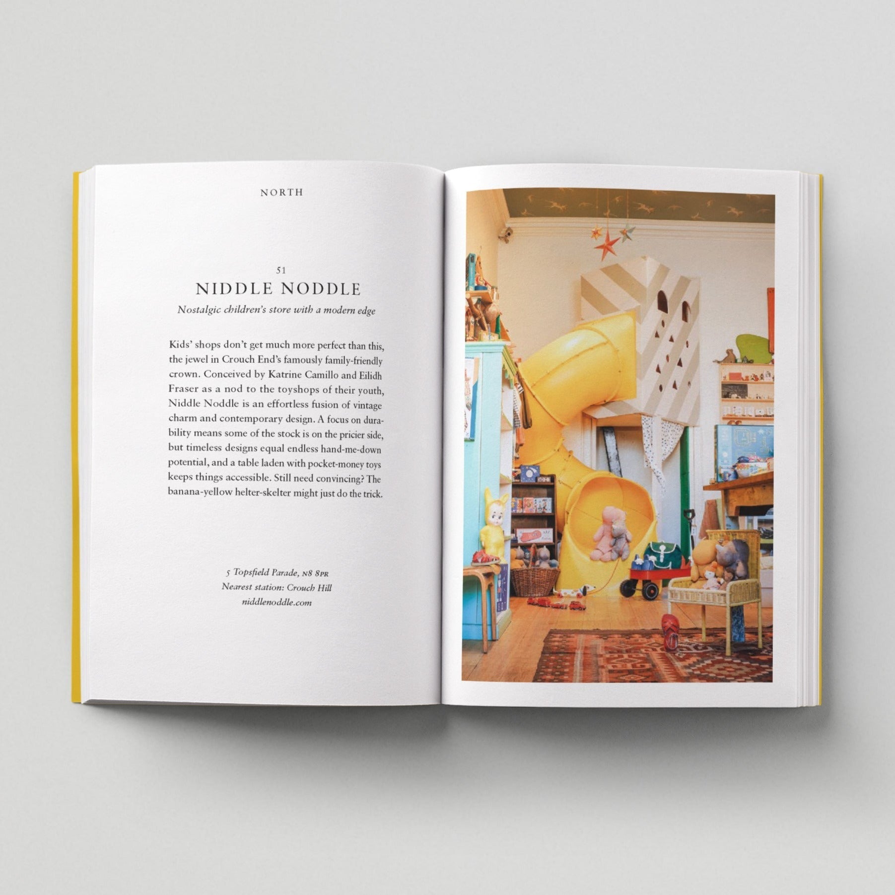 Open page of Kids London book featuring a photograph of the interior of a toy shop with toys and a yellow slide.