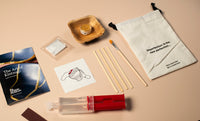 Kintsugi repair kit with tools and materials on a light pink surface
