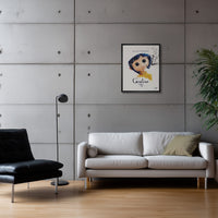 Framed poster of the film Coraline on a grey concrete wall above a white leather sofa