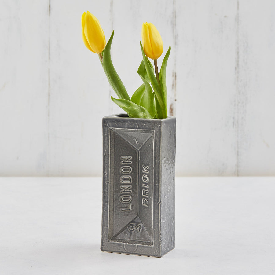 Two yellow tulips in a grey brick-shaped vase.