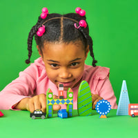 A child playing with a collection of colourful wooden blocks in the shape of London landmarks on a green backdrop.