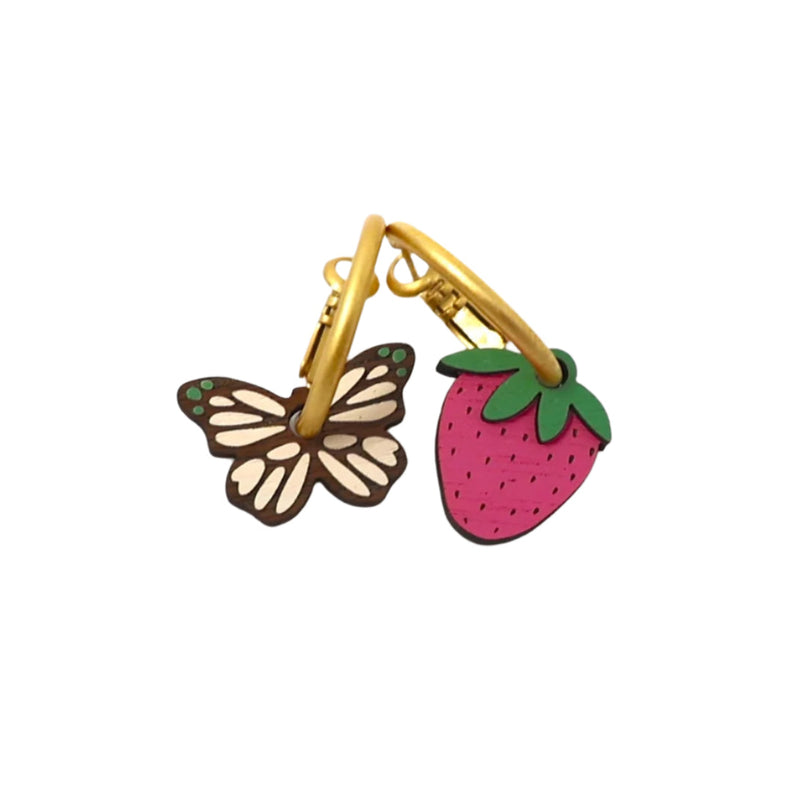 Butterfly and strawberry-shaped earrings with gold hoops on a white background