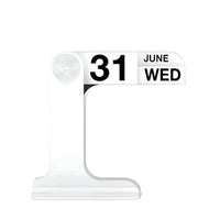 A modern minimalist desktop calendar stand made of clear acrylic, displaying the date '31 JUNE WED' in bold black text on a white panel, set against a solid white background.