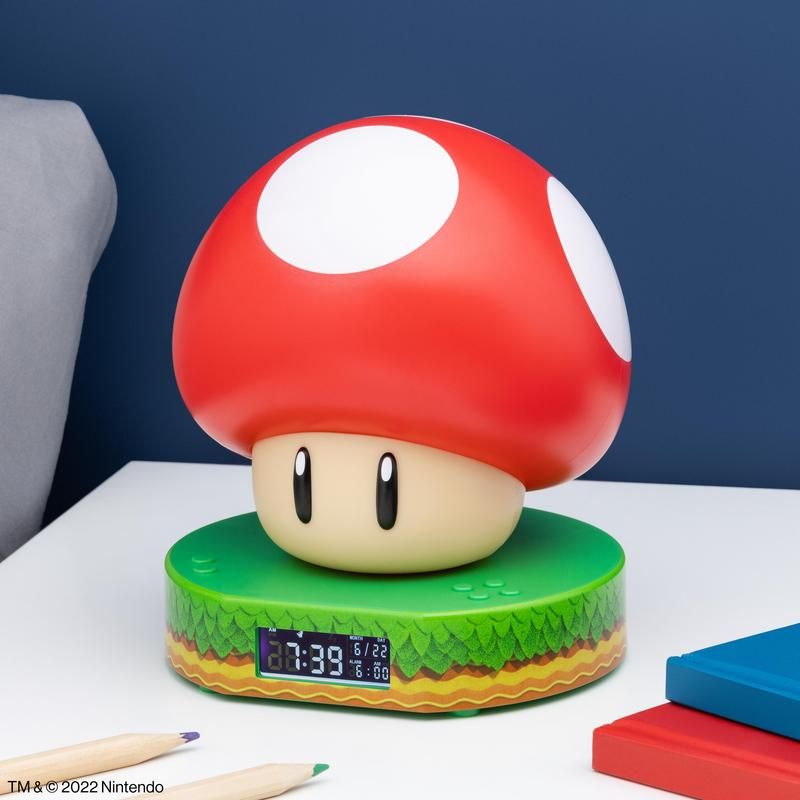 Red and white mushroom-shaped clock on a green base with a blue background