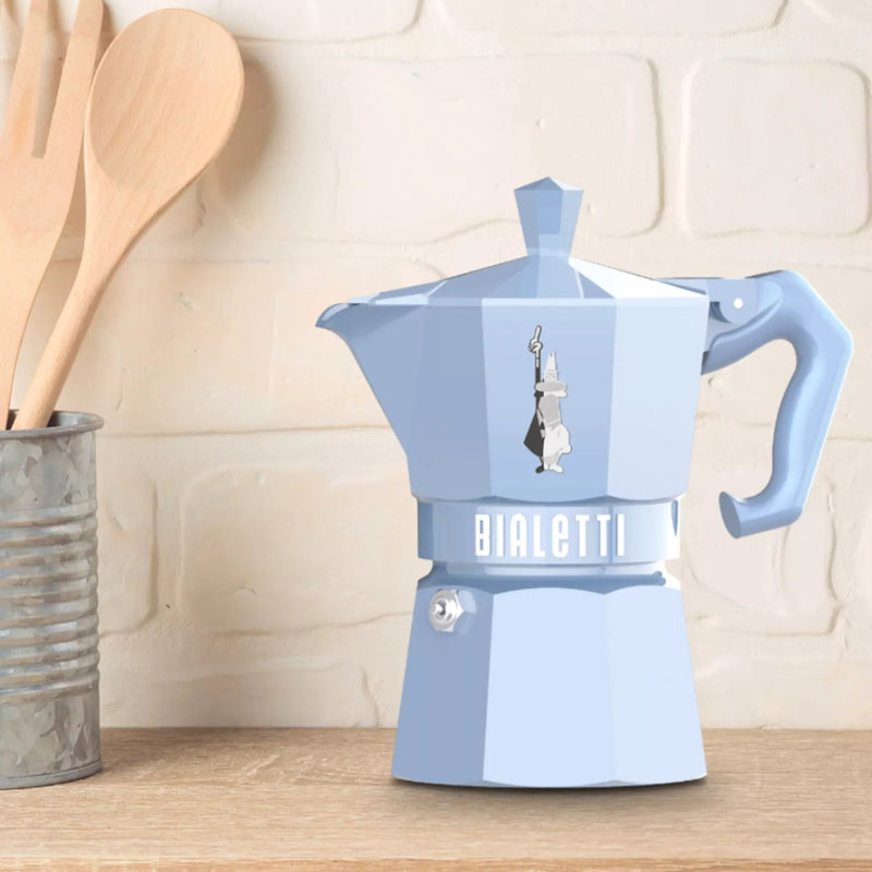 Blue Bialetti coffee maker on a kitchen counter with wooden utensils in the background.