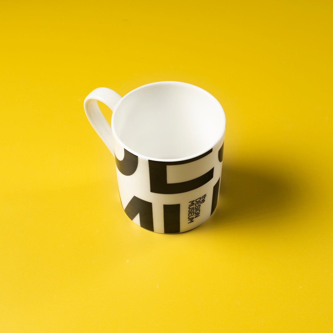 Mug on a yellow background with black lettering