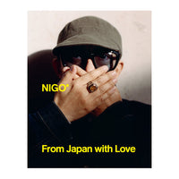 Front cover of Nigo: From Japan with Love exhibition catalogue with yellow writing and a photo of a man covering his face with his hands