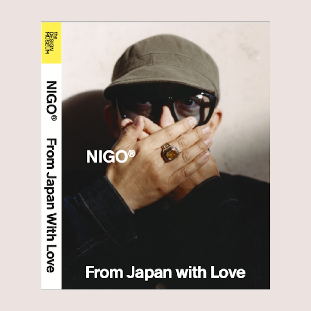Person wearing a cap and sunglasses with 'NIGO' branding on a beige background