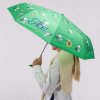 Person holding a green patterned umbrella featuring Snoopy