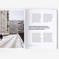 Open page of Panelki book featuring a photograph of a brutalist building and a page with text.