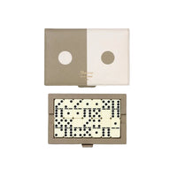 A rectangular game set with a split beige and cream cover and a set of black-and-cream domino tiles arranged inside, photographed on a clean white background.