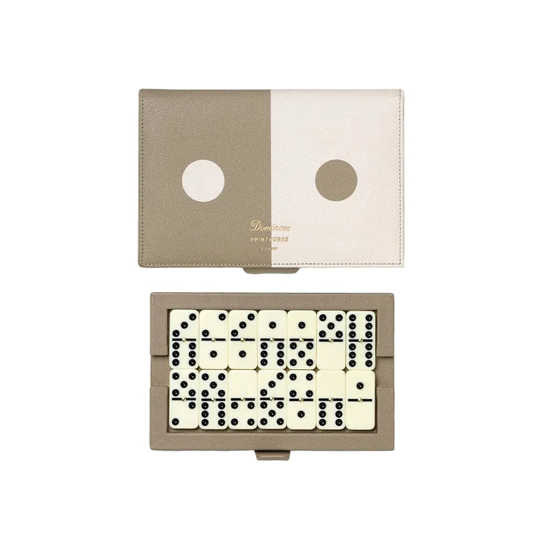 A rectangular game set with a split beige and cream cover and a set of black-and-cream domino tiles arranged inside, photographed on a clean white background.