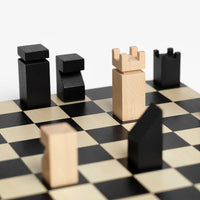 Minimal wooden chess pieces on a black and beige checkered board against a clean white background.