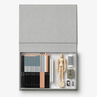 Art supply set with pencils, a mannequin, and other tools in a gray case on a white background
