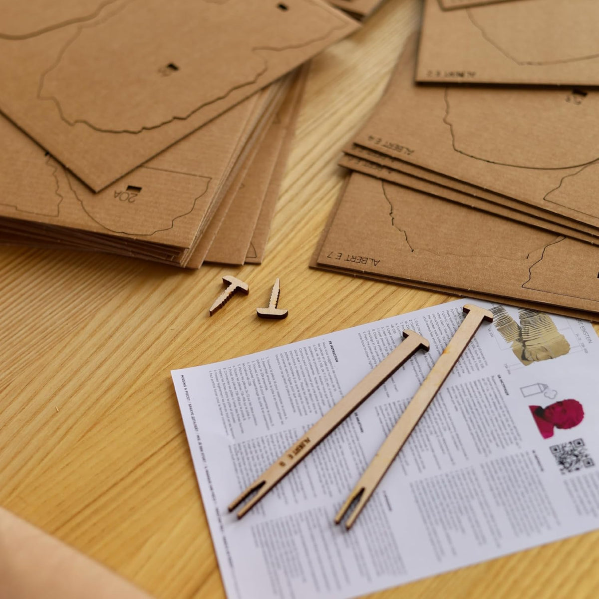 Cardboard pieces of a model camera laid on a table with instructions. 