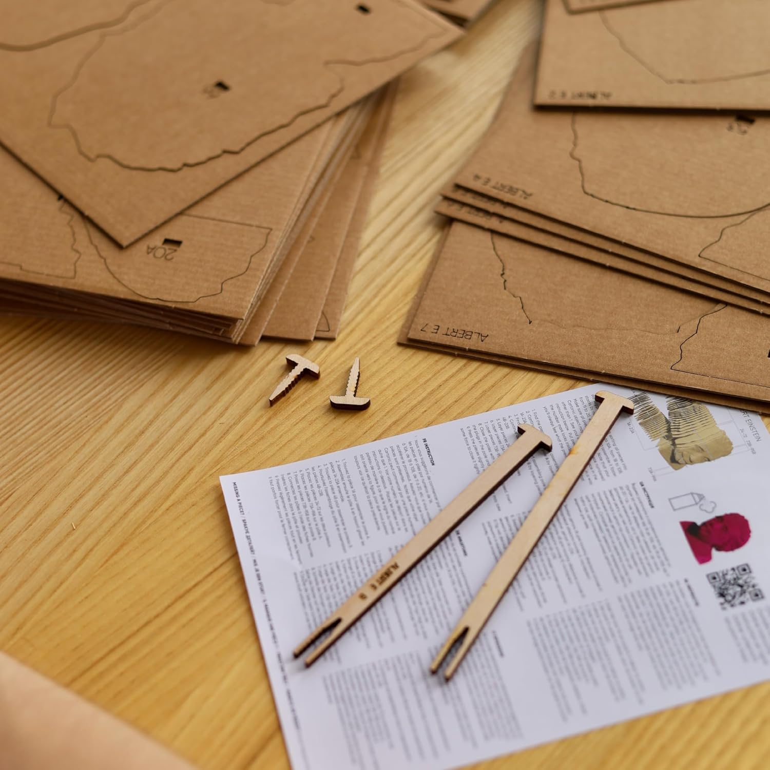 Cardboard pieces of a model camera laid on a table with instructions. 