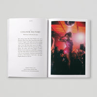 Open page of Queer London book featuring a photograph of a person dancing on a stage amongst a crowd of people underneath a disco ball. 