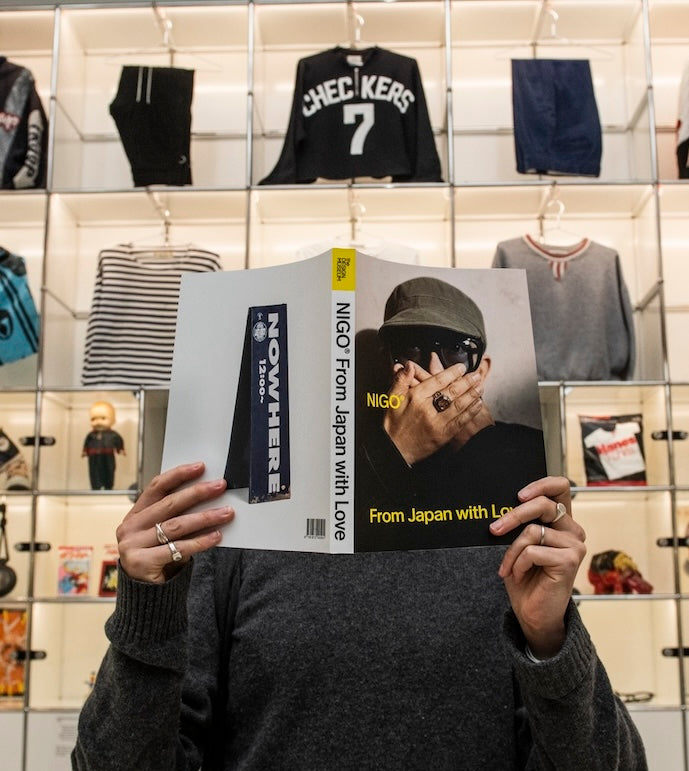 Person holding a magazine with a store display of clothing in the background