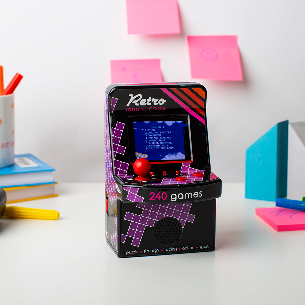 Retro-style handheld gaming console with 240 games on a desk with stationery items.